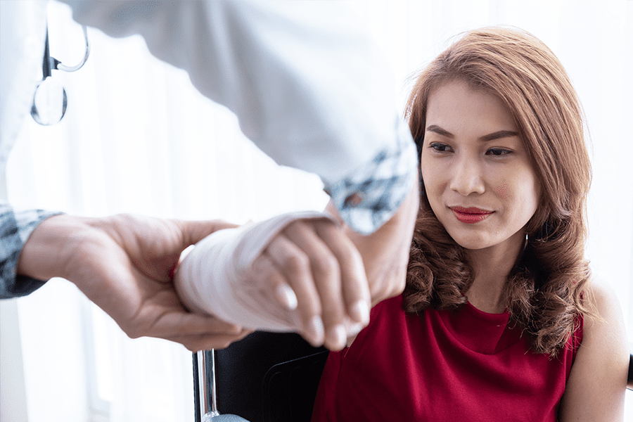 A female patient's injured wrist is wrapped in a cast.