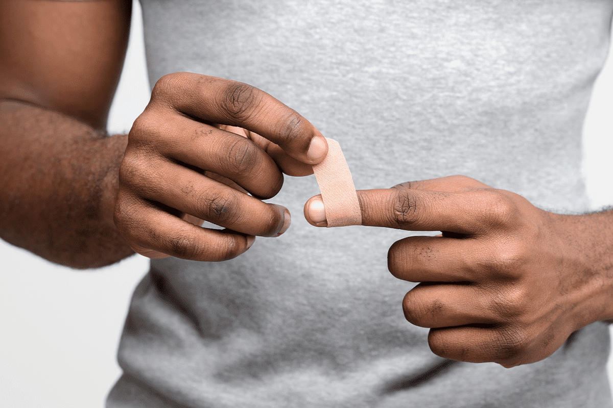 Man wraps injured finger with a bandage.
