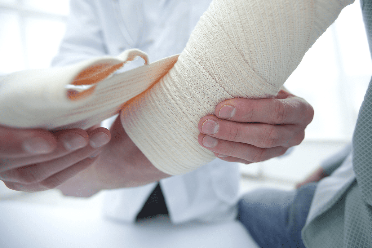 Doctor wraps injured arm with a bandage around the elbow.